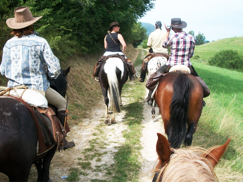 À cheval, avec un âne de bât