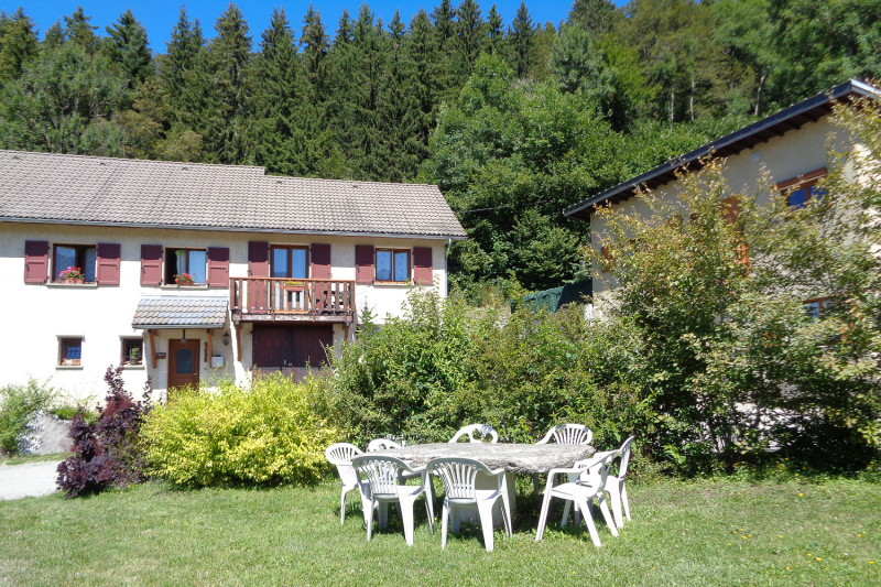 Gîte avec balcon, petit jardin privatif & salon de jardin à l'arrière plan. Jardin & aire de jeu en commun au 1er plan.